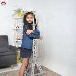 Child holding a small Eiffel Tower model in a room with a gray sofa and white shelves.