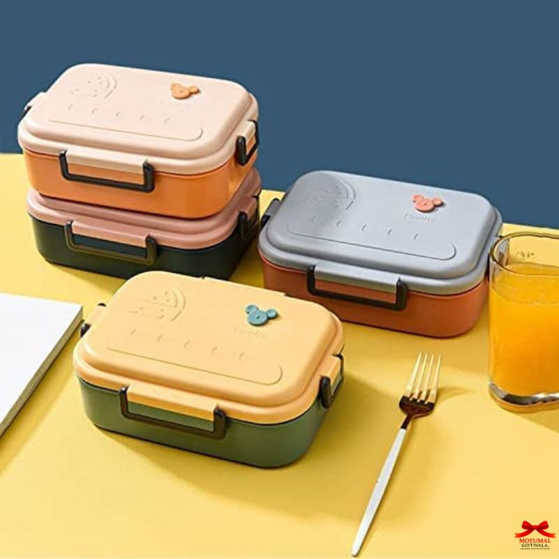 Set of colorful lunch boxes on a yellow surface with a glass of juice and fork.