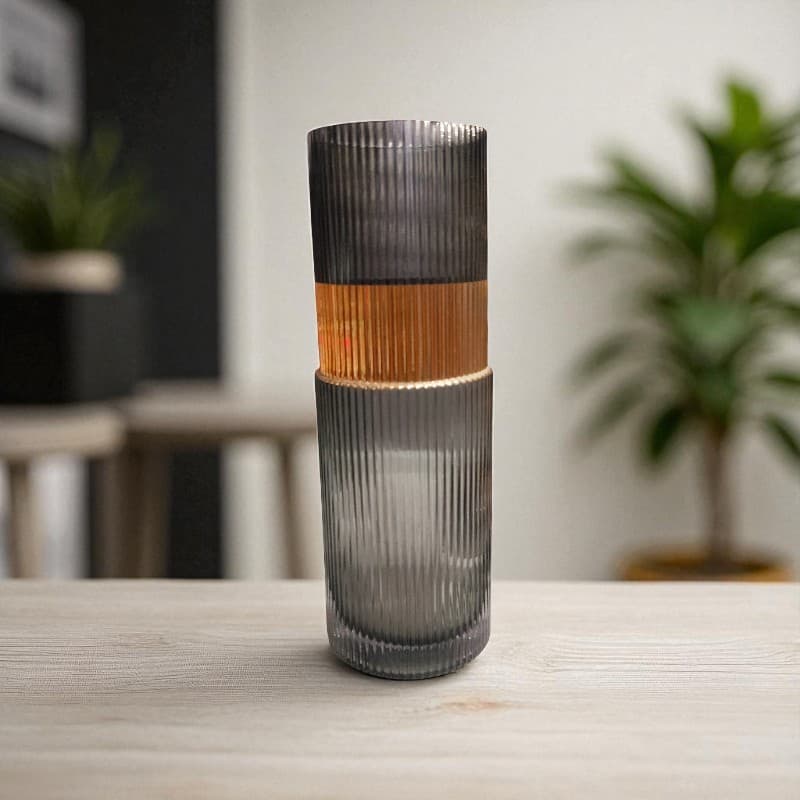 Tall ribbed glass vase with two-tone design on a wooden surface.