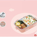 Pink bento box with compartments of food on a pink background