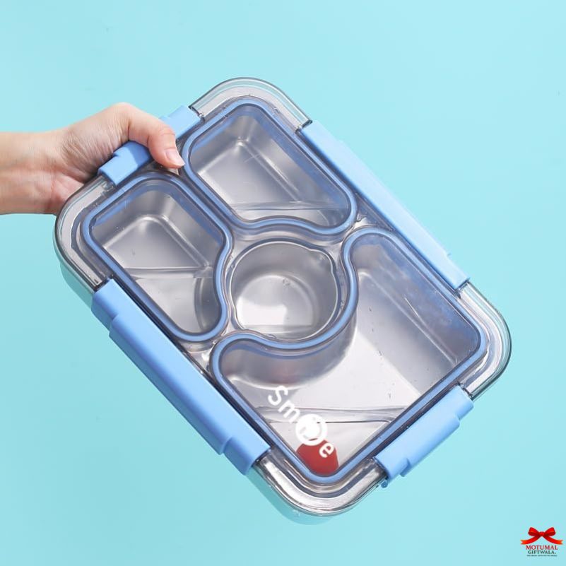 Stainless steel lunch box with compartments held by a hand against a light blue background