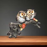 Side angle of three owl statue with floral tree design