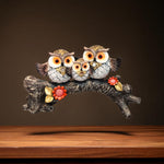 Front view of owl family showpiece on tree branch with flowers
