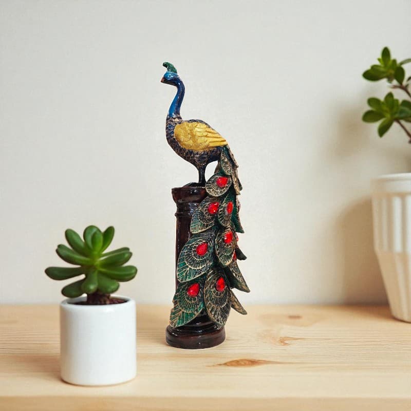 Decorative peacock sculpture on a wooden surface with a plant in the background