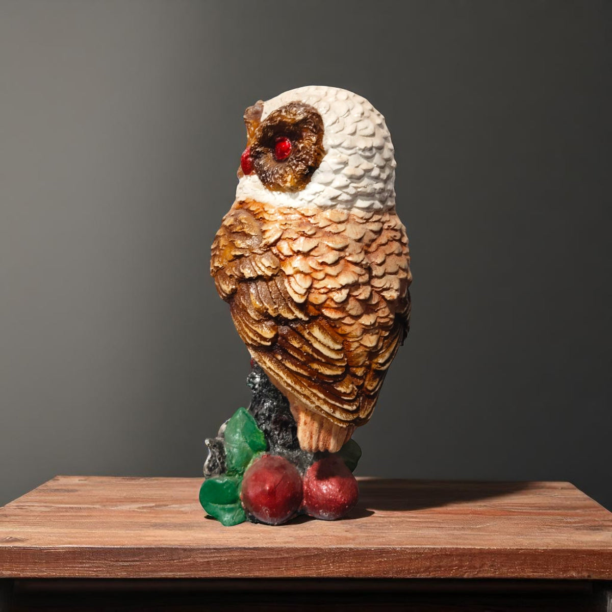 Side view of owl statue with textured wings and glossy red eyes