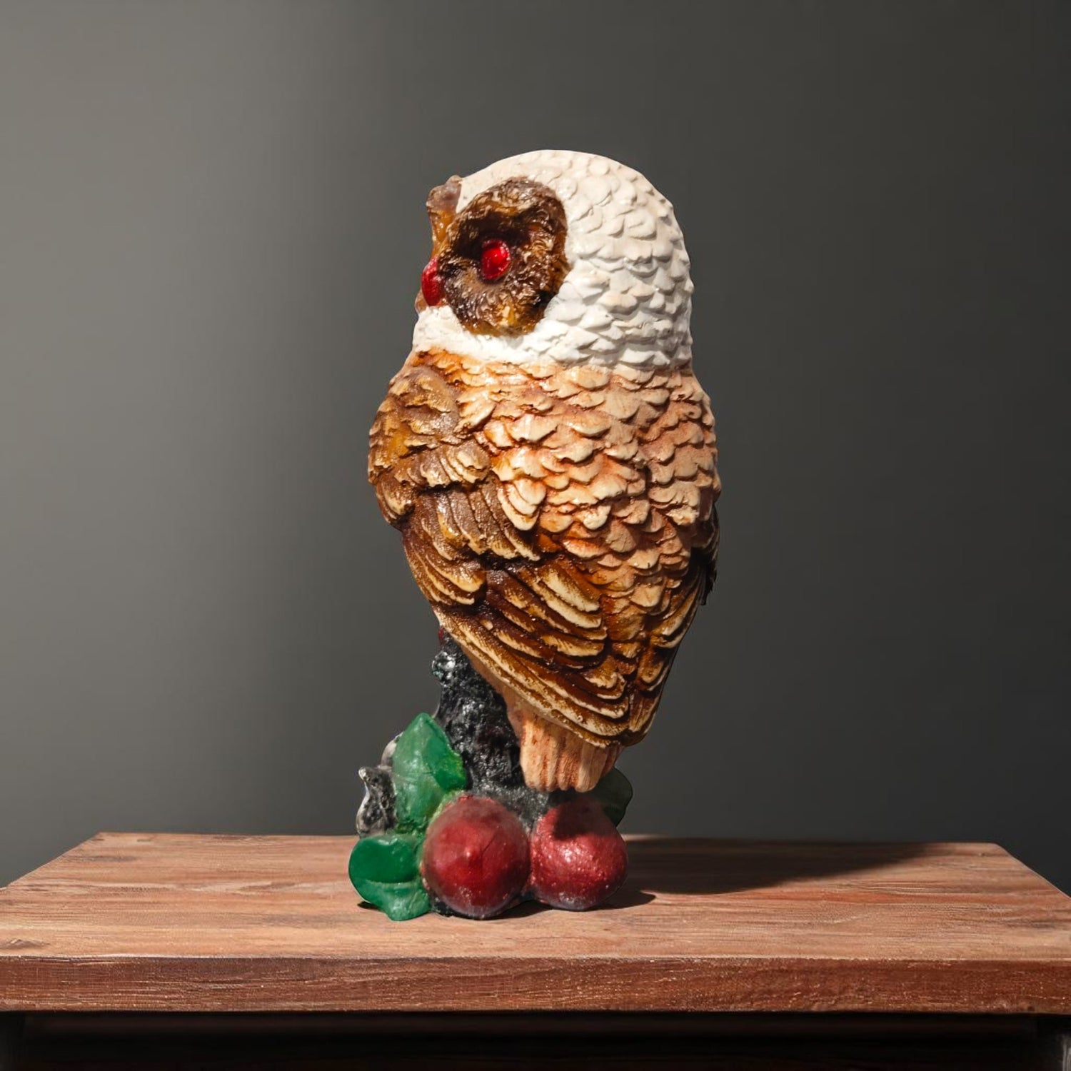 Side view of owl statue with textured wings and glossy red eyes