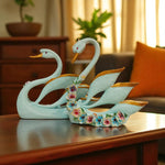 Decorative swan figurines on a wooden surface with a blurred indoor background