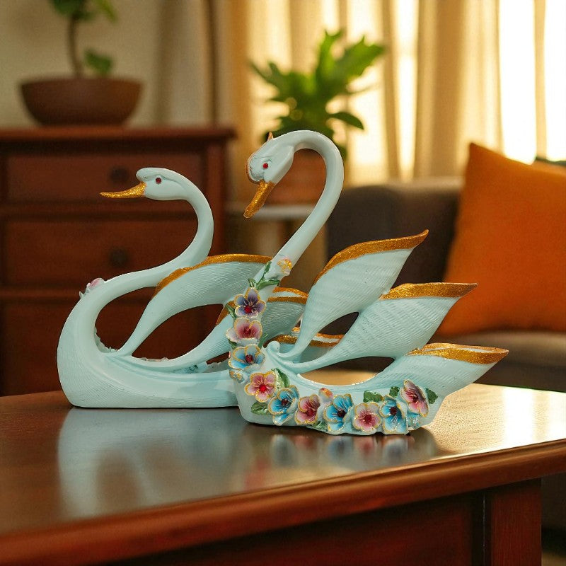Decorative swan figurines on a wooden surface with a blurred indoor background
