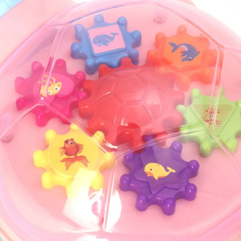 Colorful bath toys with sea creature designs in a pink container