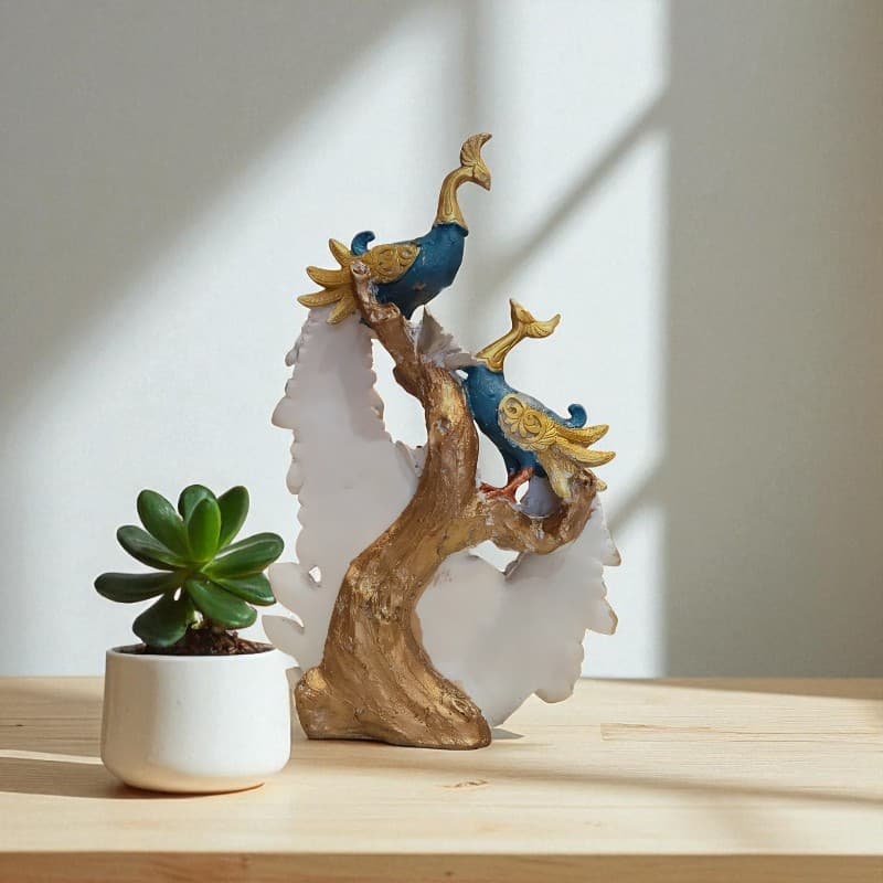 Decorative peacock sculpture on a branch with a potted plant on a wooden surface.