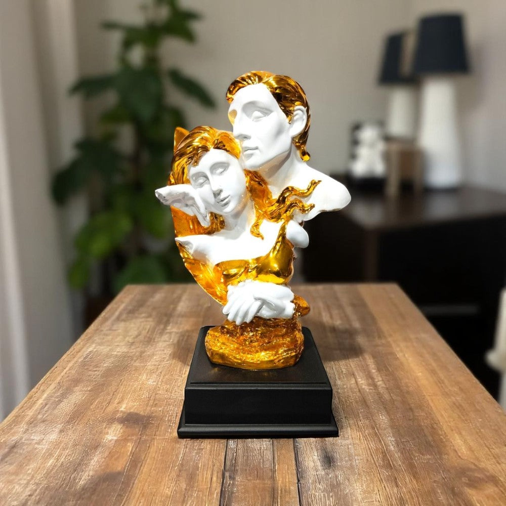 Golden white couple bust sculpture on wooden table with plants