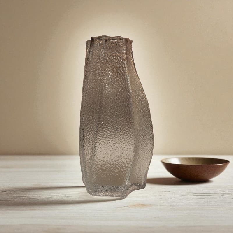 Textured glass vase on a wooden surface with a neutral background