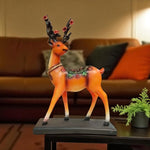 Decorative deer figurine with floral decorations on a table in a living room setting.