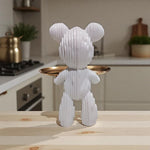 White teddy bear-shaped object with a gold tray on a wooden surface in a kitchen setting