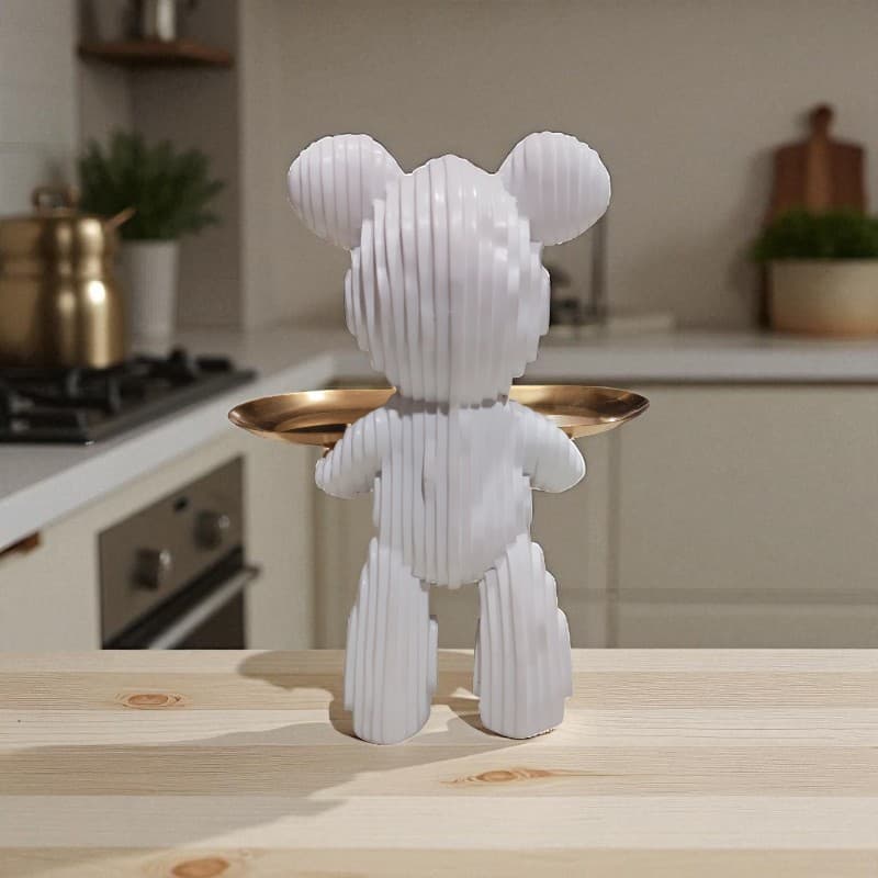 White teddy bear-shaped object with a gold tray on a wooden surface in a kitchen setting