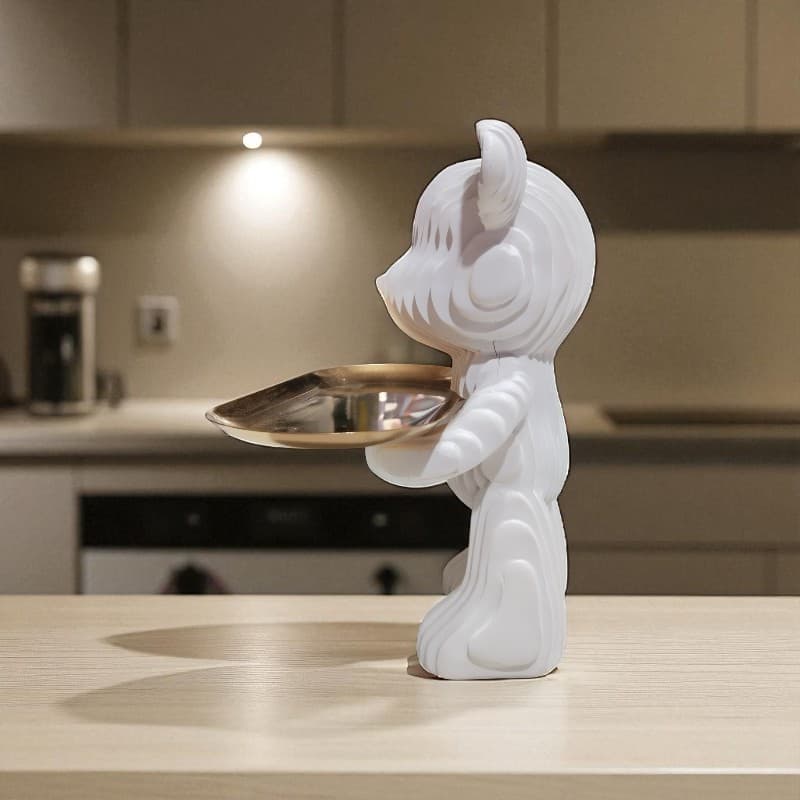 White ceramic cat-shaped object holding a gold tray on a kitchen counter.