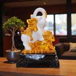 Decorative statue of a lion with gold accents on a dark base, placed on a wooden surface.