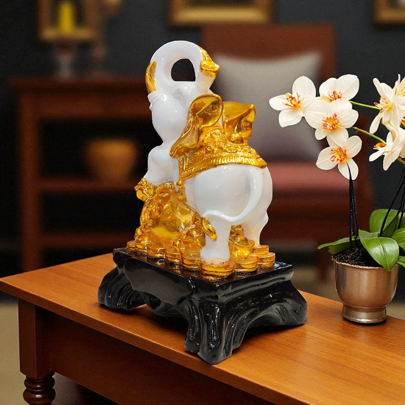 Decorative sculpture of a white and gold figure on a wooden table with flowers in the background