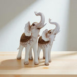 Two decorative elephant figurines with intricate patterns on a wooden surface.