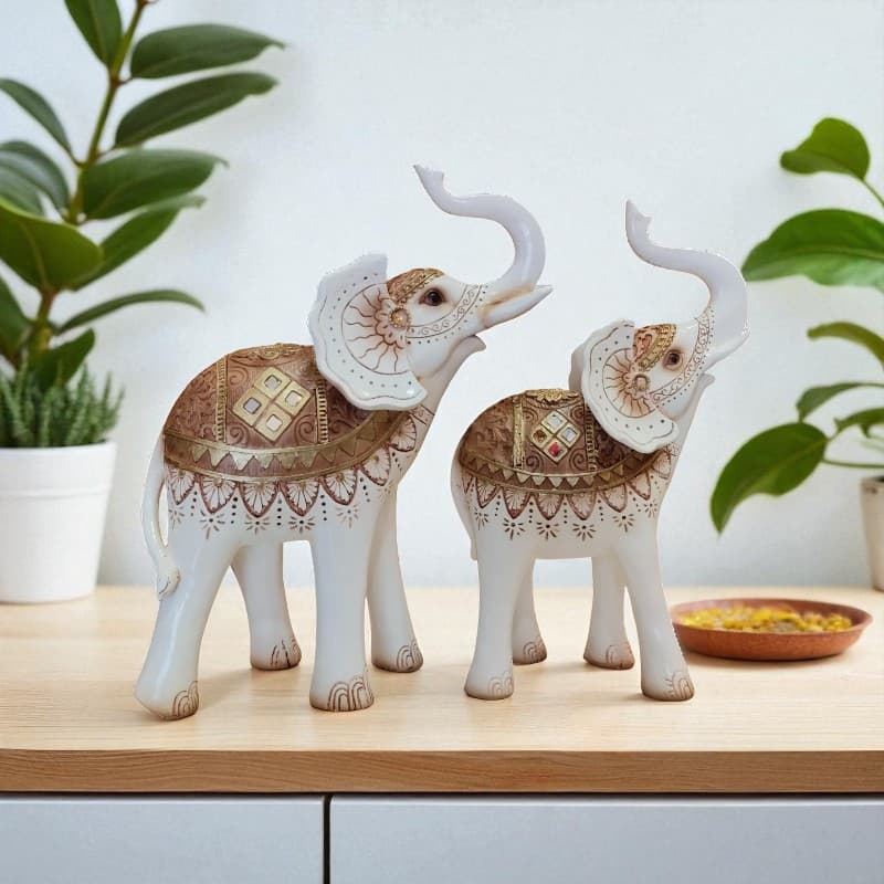 Decorative ceramic elephants with intricate patterns on a wooden surface with plants in the background.