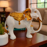 Decorative white elephant figurine with gold accents on a table in a living room setting.