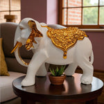 Decorative white elephant figurine with gold accents on a table in a living room.