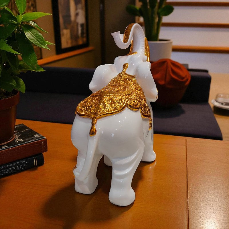 Decorative white elephant figurine with gold accents on a wooden table.