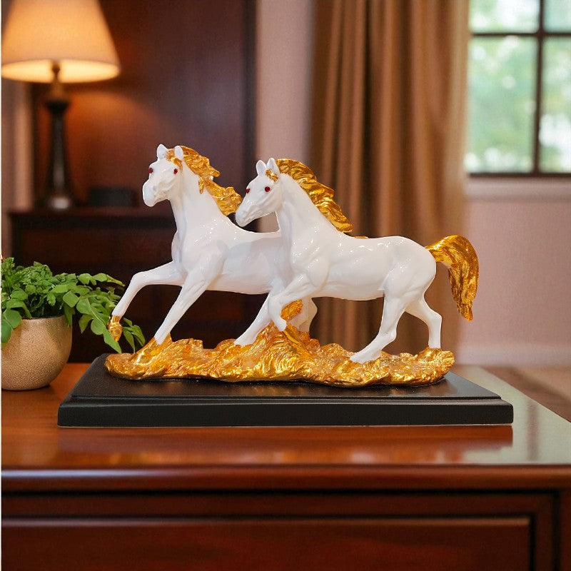 Decorative sculpture of two white horses with gold manes on a black base, placed on a wooden surface.