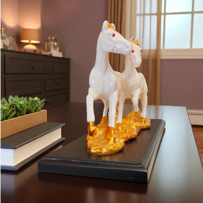 Decorative sculpture of two white horses on a gold rock base on a table.