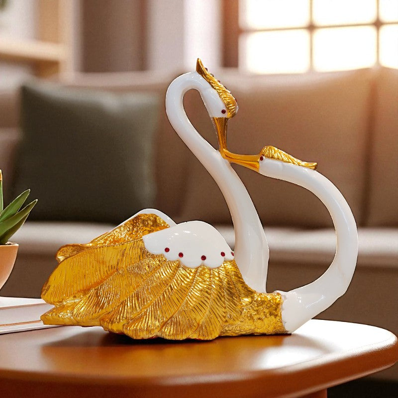 Decorative sculpture of two swans on a shell with gold accents on a table.