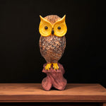 Front view of owl showpiece with yellow eyes on wooden base