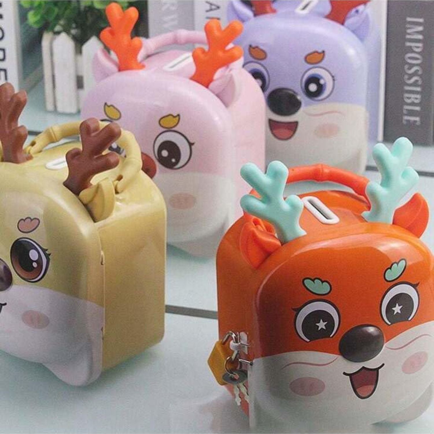 Colorful reindeer piggy banks in orange, purple, pink, and yellow displayed on glass table, Motumal Giftwala